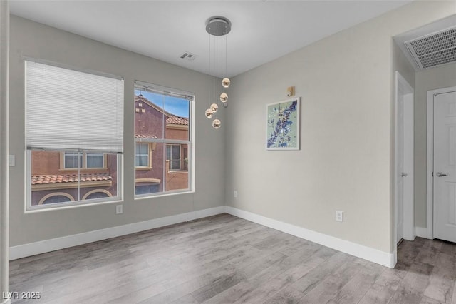 empty room featuring visible vents, baseboards, and wood finished floors