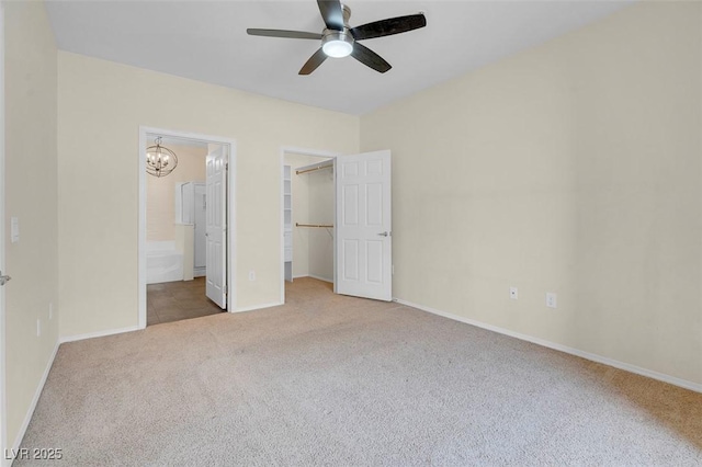 unfurnished bedroom with baseboards, a spacious closet, a closet, ensuite bathroom, and carpet flooring