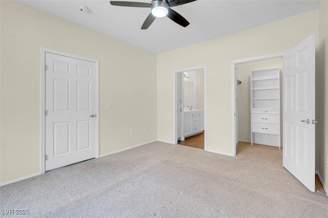 unfurnished bedroom with a spacious closet, baseboards, ensuite bathroom, and carpet