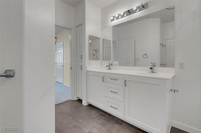 bathroom featuring double vanity, baseboards, and a sink