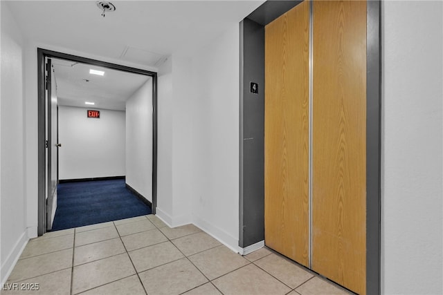 corridor featuring light tile patterned floors, elevator, and baseboards