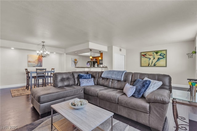 living area featuring baseboards, a chandelier, and wood finished floors