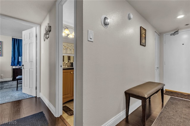 hallway with baseboards, dark wood finished floors, a sink, and recessed lighting