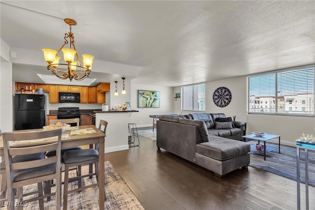 living room with dark wood-style floors, a chandelier, a textured ceiling, and baseboards