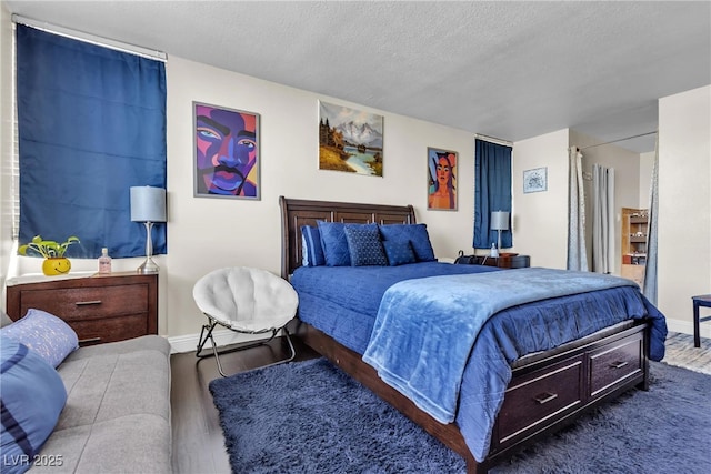 bedroom with a textured ceiling, baseboards, and wood finished floors