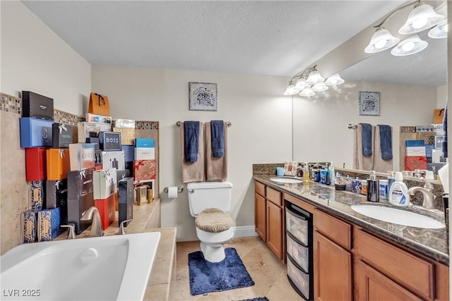 bathroom with tiled tub, a sink, a textured ceiling, and toilet