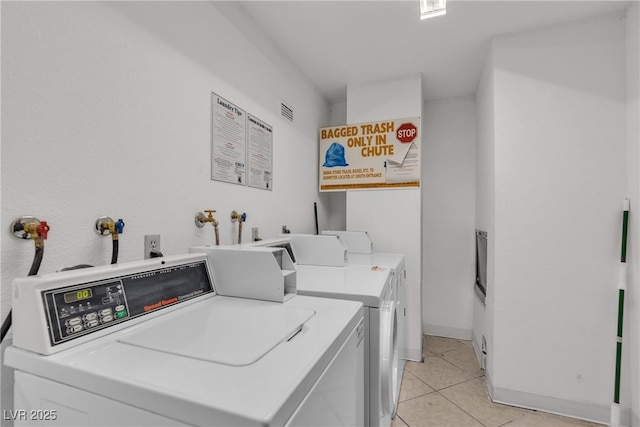 shared laundry area featuring washer and dryer, light tile patterned flooring, visible vents, and baseboards