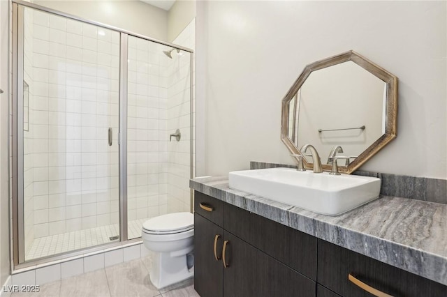 bathroom featuring tile patterned flooring, a shower stall, toilet, and vanity