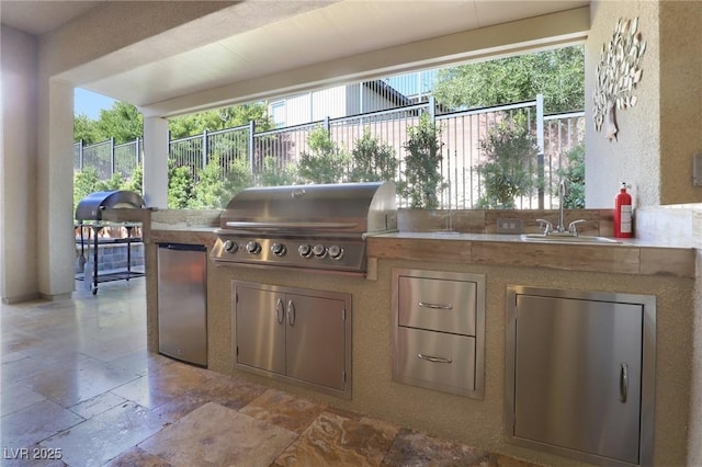 view of patio / terrace featuring a sink, grilling area, an outdoor kitchen, and fence