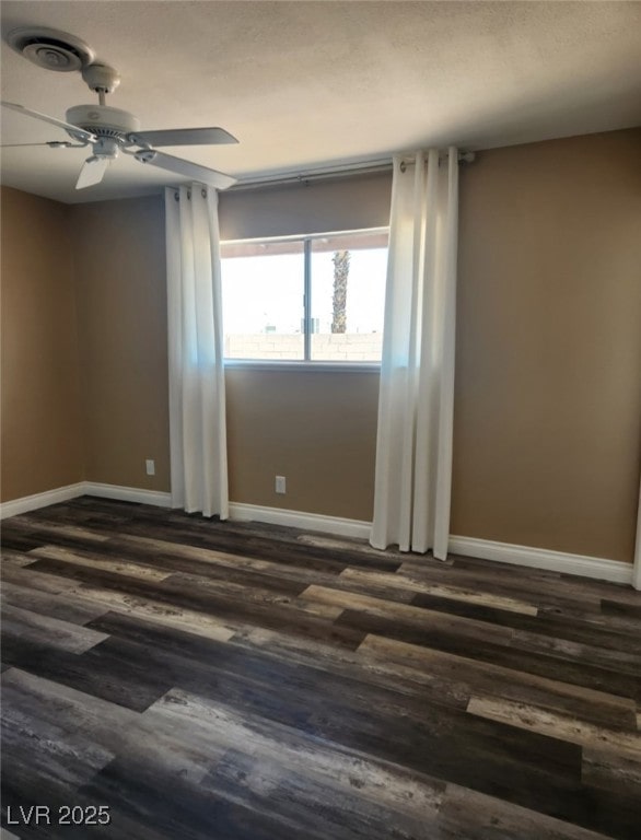 unfurnished room featuring dark wood-style floors, baseboards, visible vents, and ceiling fan