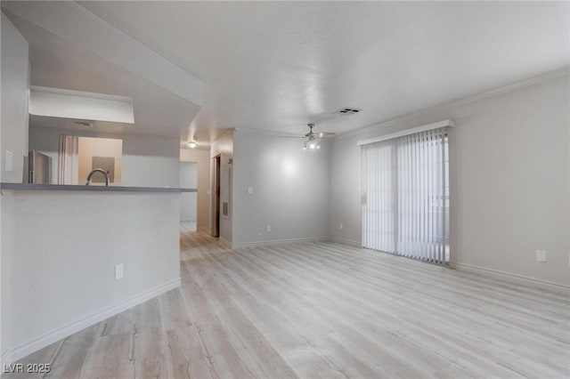 unfurnished living room featuring visible vents, ceiling fan, a sink, light wood-type flooring, and baseboards