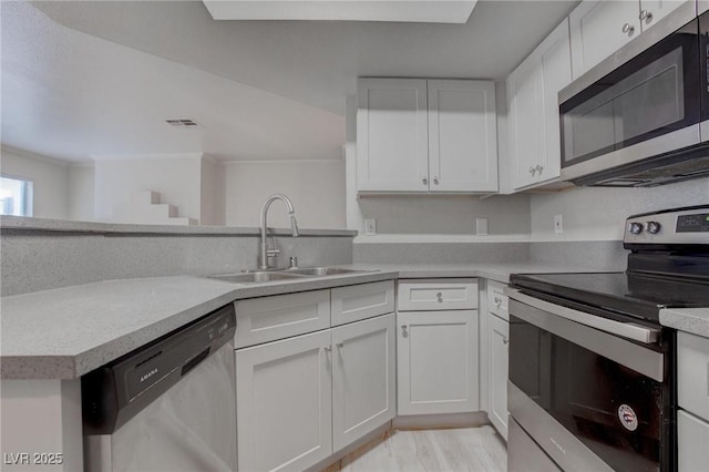 kitchen with white cabinetry, appliances with stainless steel finishes, light countertops, and a sink