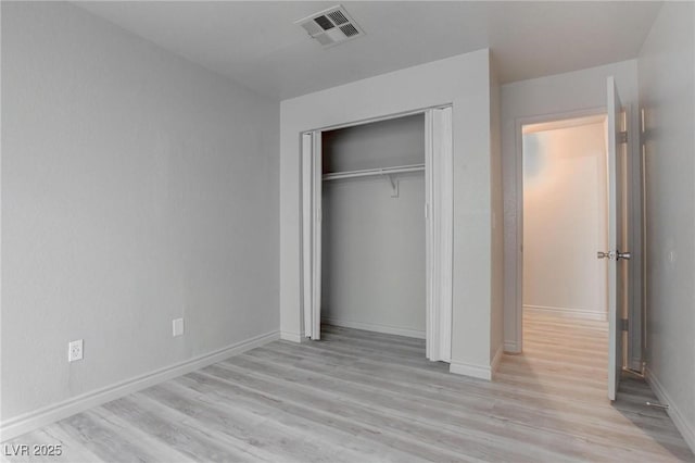 unfurnished bedroom featuring light wood-style flooring, a closet, visible vents, and baseboards