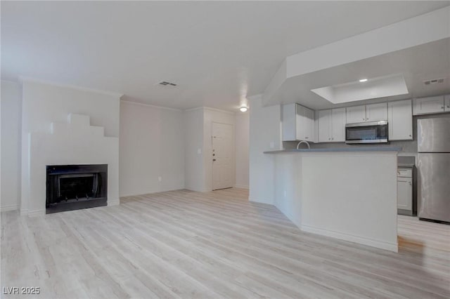 kitchen featuring visible vents, a fireplace, appliances with stainless steel finishes, and light wood-style flooring