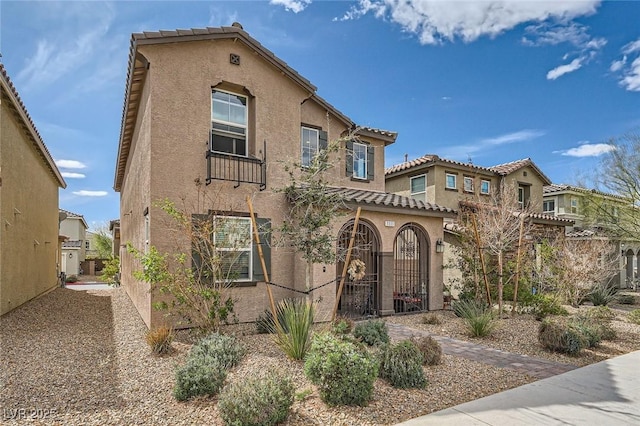 mediterranean / spanish-style house with fence, a tiled roof, and stucco siding