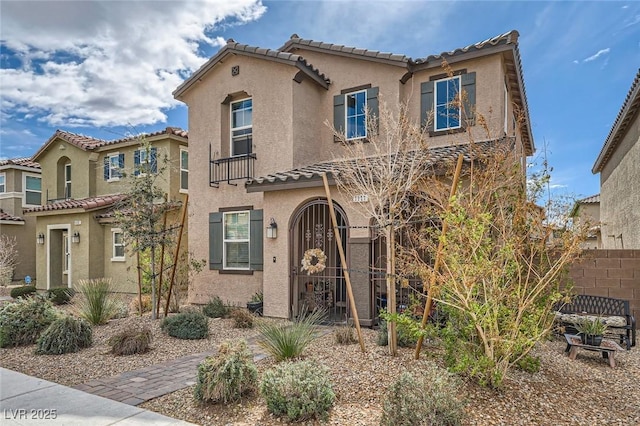 mediterranean / spanish-style house featuring a tile roof, fence, and stucco siding