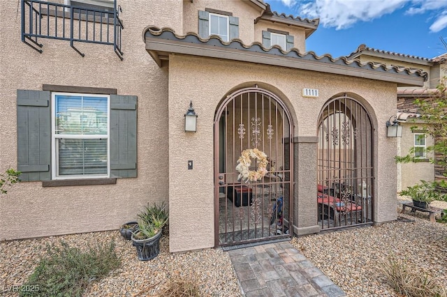 entrance to property featuring a tile roof and stucco siding