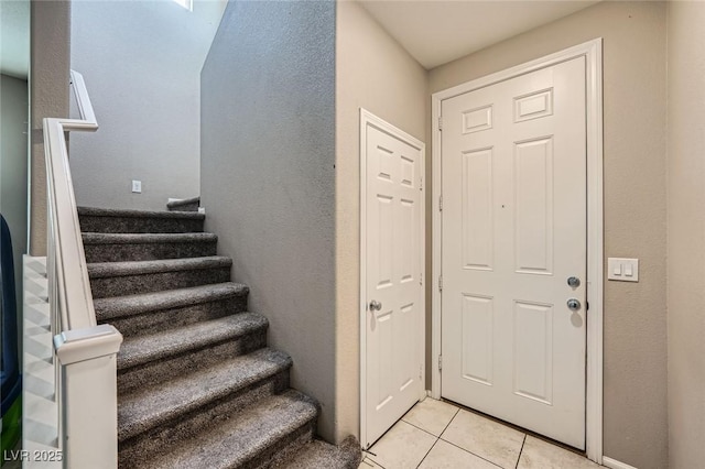 foyer featuring light tile patterned flooring and stairway