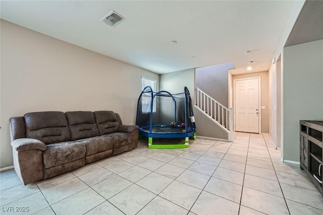 living area with stairs, light tile patterned floors, visible vents, and baseboards