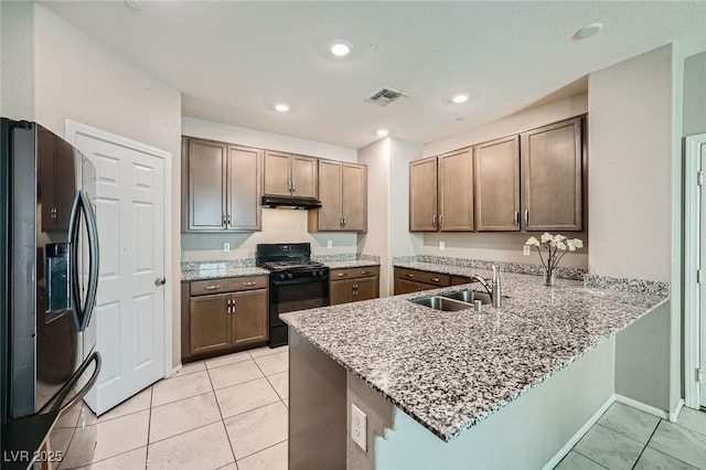 kitchen featuring visible vents, a peninsula, under cabinet range hood, black appliances, and a sink