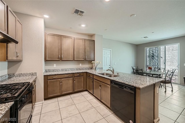 kitchen with light stone counters, a peninsula, a sink, visible vents, and black appliances