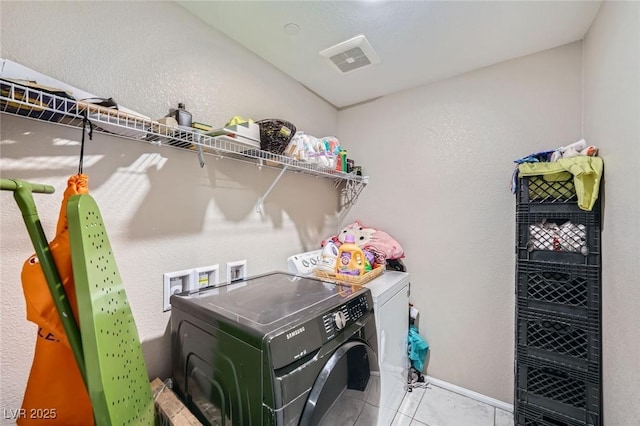 washroom with washing machine and clothes dryer, light tile patterned floors, visible vents, laundry area, and baseboards