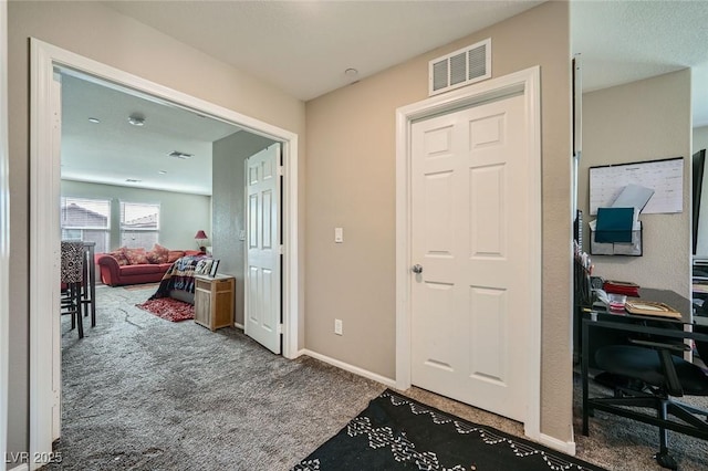 hall featuring baseboards, visible vents, and carpet flooring