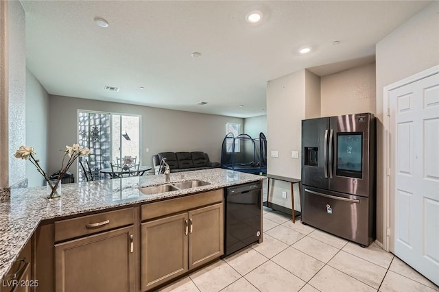 kitchen with visible vents, dishwasher, light stone countertops, stainless steel refrigerator with ice dispenser, and a sink