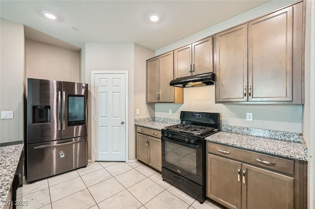 kitchen featuring black gas range, under cabinet range hood, stainless steel fridge, and light stone countertops