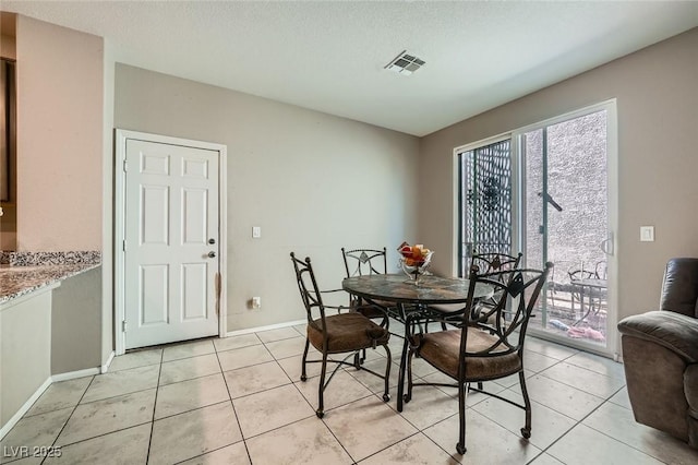 dining space featuring light tile patterned floors, baseboards, visible vents, and a textured ceiling