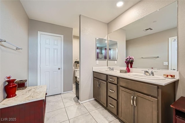 full bathroom featuring toilet, double vanity, visible vents, and a sink