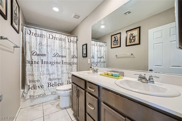 bathroom with toilet, double vanity, a sink, and visible vents