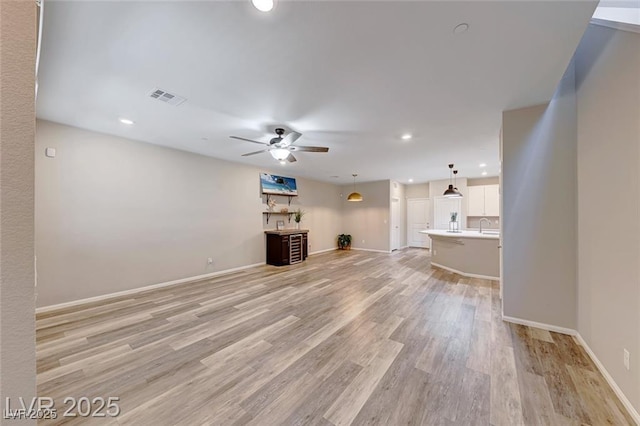 unfurnished living room with baseboards, a ceiling fan, visible vents, and light wood-style floors