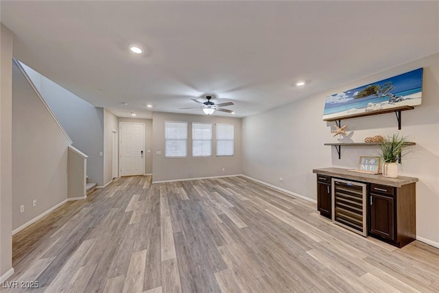 unfurnished living room featuring beverage cooler, light wood-style flooring, baseboards, and stairs