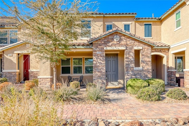 view of front facade featuring stone siding, a tiled roof, and stucco siding