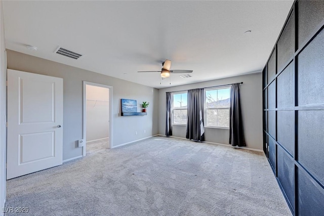 unfurnished bedroom featuring a ceiling fan, a spacious closet, visible vents, and carpet flooring