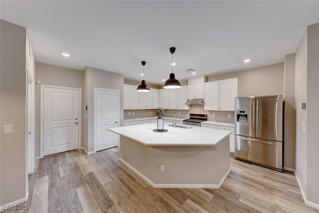 kitchen featuring appliances with stainless steel finishes, light countertops, under cabinet range hood, white cabinetry, and a sink