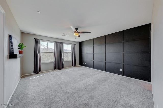 carpeted spare room featuring a ceiling fan, visible vents, and baseboards