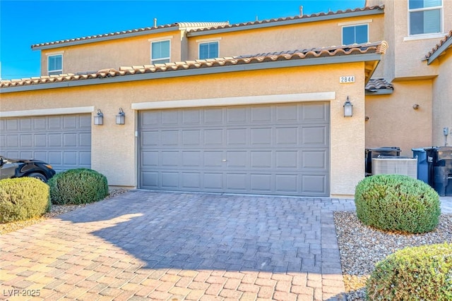 garage featuring cooling unit and decorative driveway