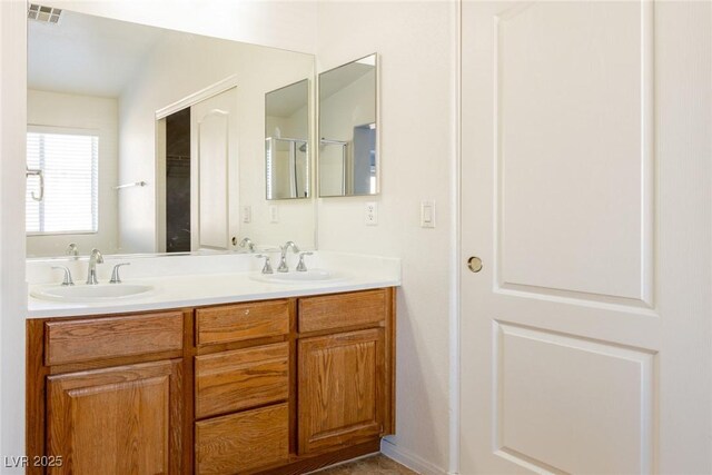 bathroom with double vanity, visible vents, and a sink