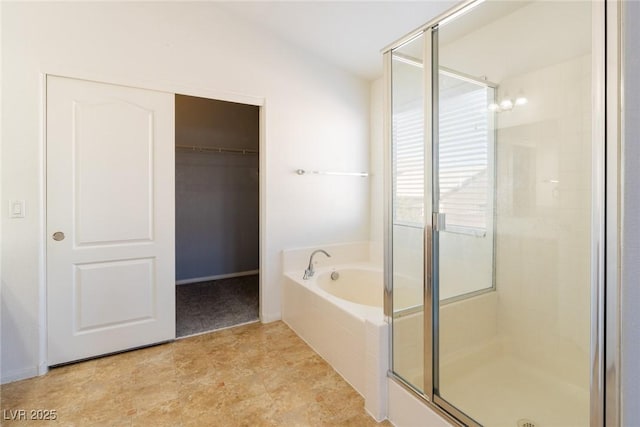 bathroom featuring a walk in closet, a garden tub, and a stall shower