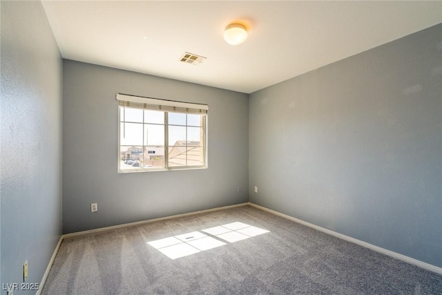 carpeted spare room featuring visible vents and baseboards