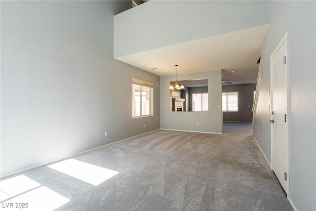 carpeted empty room with baseboards and an inviting chandelier