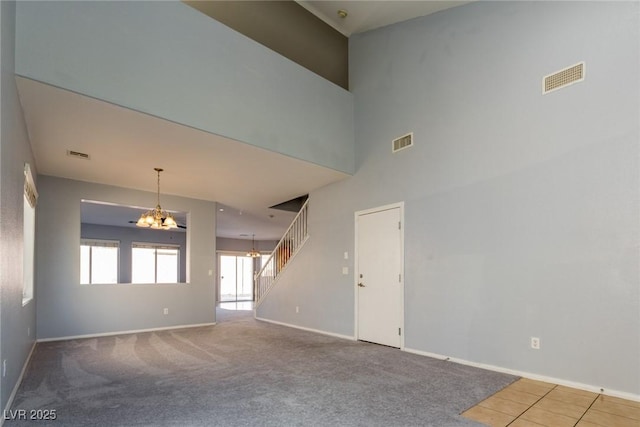 carpeted spare room with visible vents, stairs, and baseboards