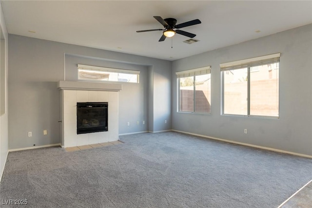 unfurnished living room featuring visible vents, baseboards, carpet flooring, a tile fireplace, and a ceiling fan