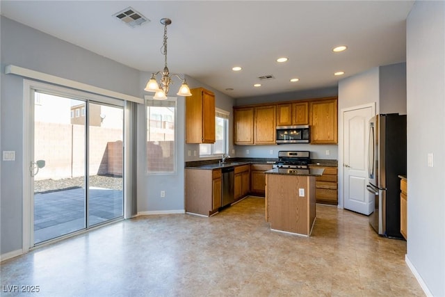 kitchen featuring visible vents, a sink, dark countertops, a center island, and stainless steel appliances