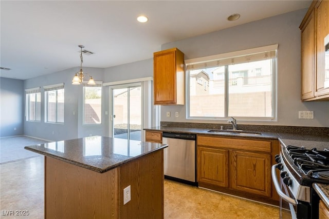 kitchen with a kitchen island, dark stone counters, brown cabinetry, stainless steel appliances, and a sink