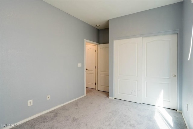 unfurnished bedroom with baseboards, light carpet, and a closet