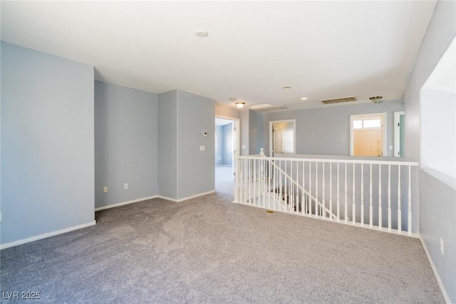 carpeted spare room featuring visible vents and baseboards