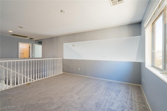 carpeted spare room featuring visible vents and baseboards